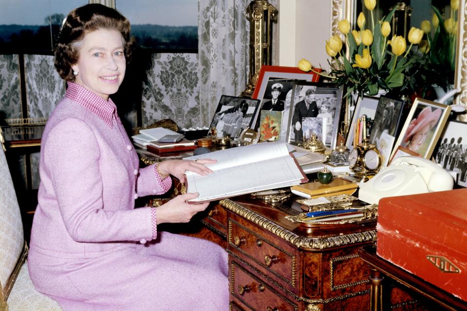 Queen Elizabeth in her sitting room at Windsor Castle looking through her diary of engagements, with a famous red box by her side (PA) (PA Archive)
