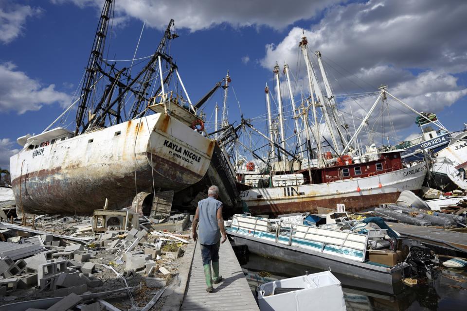 FILE - Bruce Hickey, 70, walks along the waterfront, now littered with debris including shrimp boats, in the mobile home park where he and his wife, Kathy, have a winter home on San Carlos Island, Fort Myers Beach, Fla., on Oct. 5, 2022, one week after the passage of Hurricane Ian. An overwhelming majority of the U.S. public say they have recently experienced extreme weather, and most of them attribute that to climate change, according to a new poll from The Associated Press-NORC Center for Public Affairs Research. (AP Photo/Rebecca Blackwell, File)