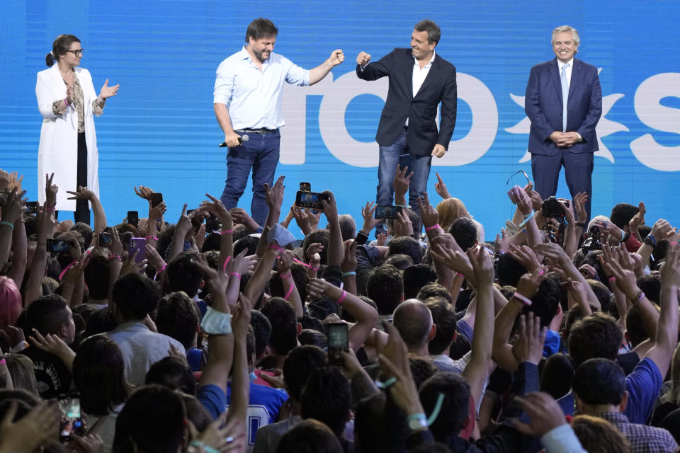 Leandro Santoro, congressional candidate for the city of Buenos Aires, second from left, fist bumps lawmaker Sergio Massa as Argentine President Alberto Fernández, right, and Gisela Marziotta, candidate for legislator for Buenos Aires, stand before supporters at the ruling party Front for Everyone campaign headquarters after polls closed for midterm legislative elections in Buenos Aires, Argentina, Sunday, Nov. 14, 2021. (AP Photo/Natacha Pisarenko)