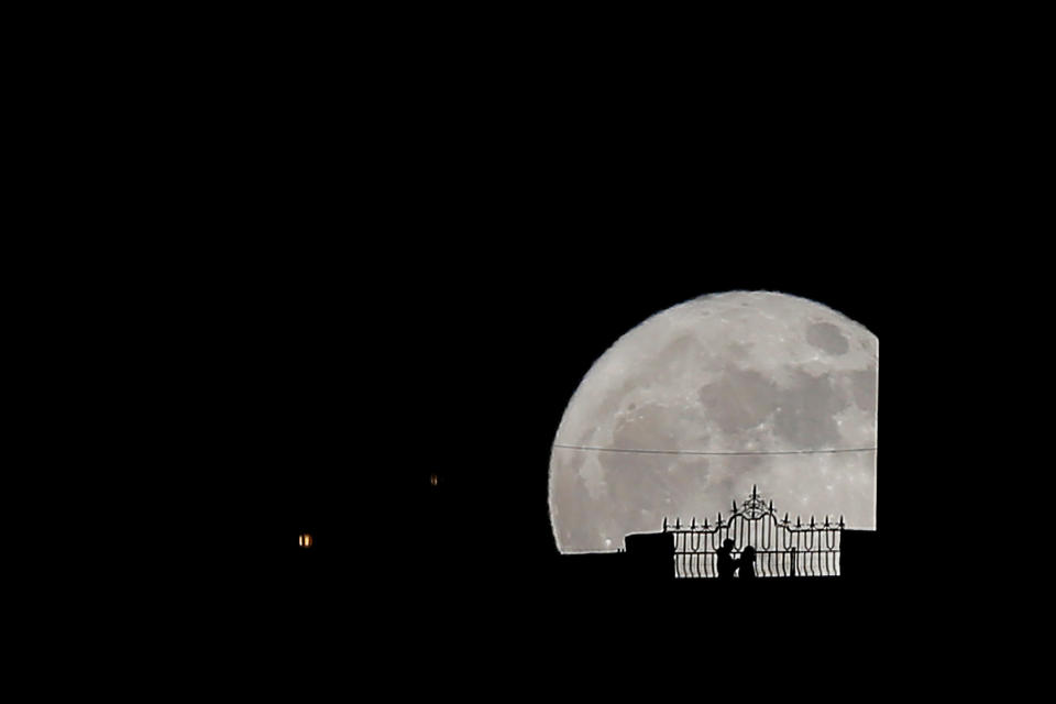 People walk along the "Puente Nuevo" (New Bridge) as they are silhouetted against the supermoon during its rise in Ronda, southern Spain, December 3, 2017