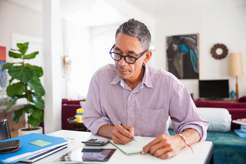 Reifer Mann mit Brille, der zu Hause an persönlichen Finanzen arbeitet