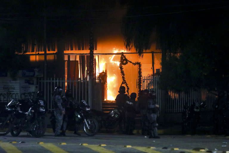 La policía, frente a una oficina gubernamental incendiada mientras los partidarios de Luis Fernando Camacho, gobernador de la región de Santa Cruz, protestan en Santa Cruz, Bolivia, el miércoles 28 de diciembre de 2022. (AP Photo/Ipa Ibáñez)