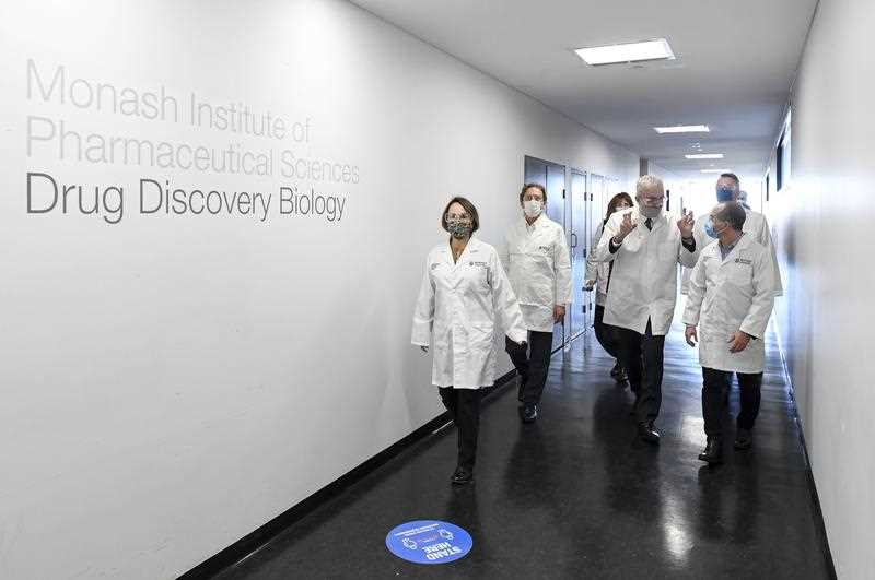 Victorian Acting Premier James Merlino (right) pictured with a group of people at Melbourne's Monash Institute of Pharmaceutical Sciences.