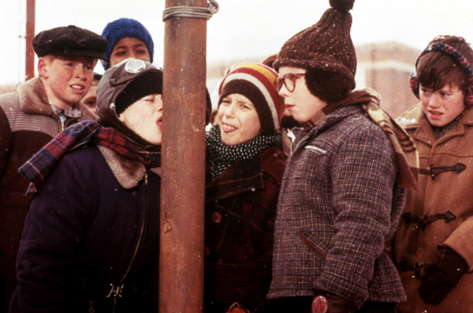 kids looking as one kid's tongue is stuck to a pole