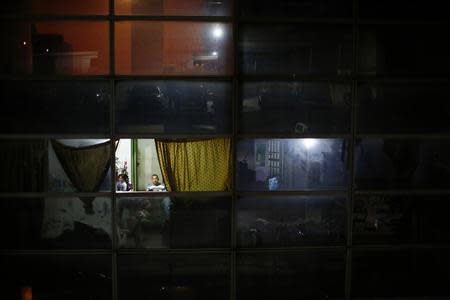 A man sits with his family in his apartment inside the "Tower of David" skyscraper in Caracas February 3, 2014. REUTERS/Jorge Silva