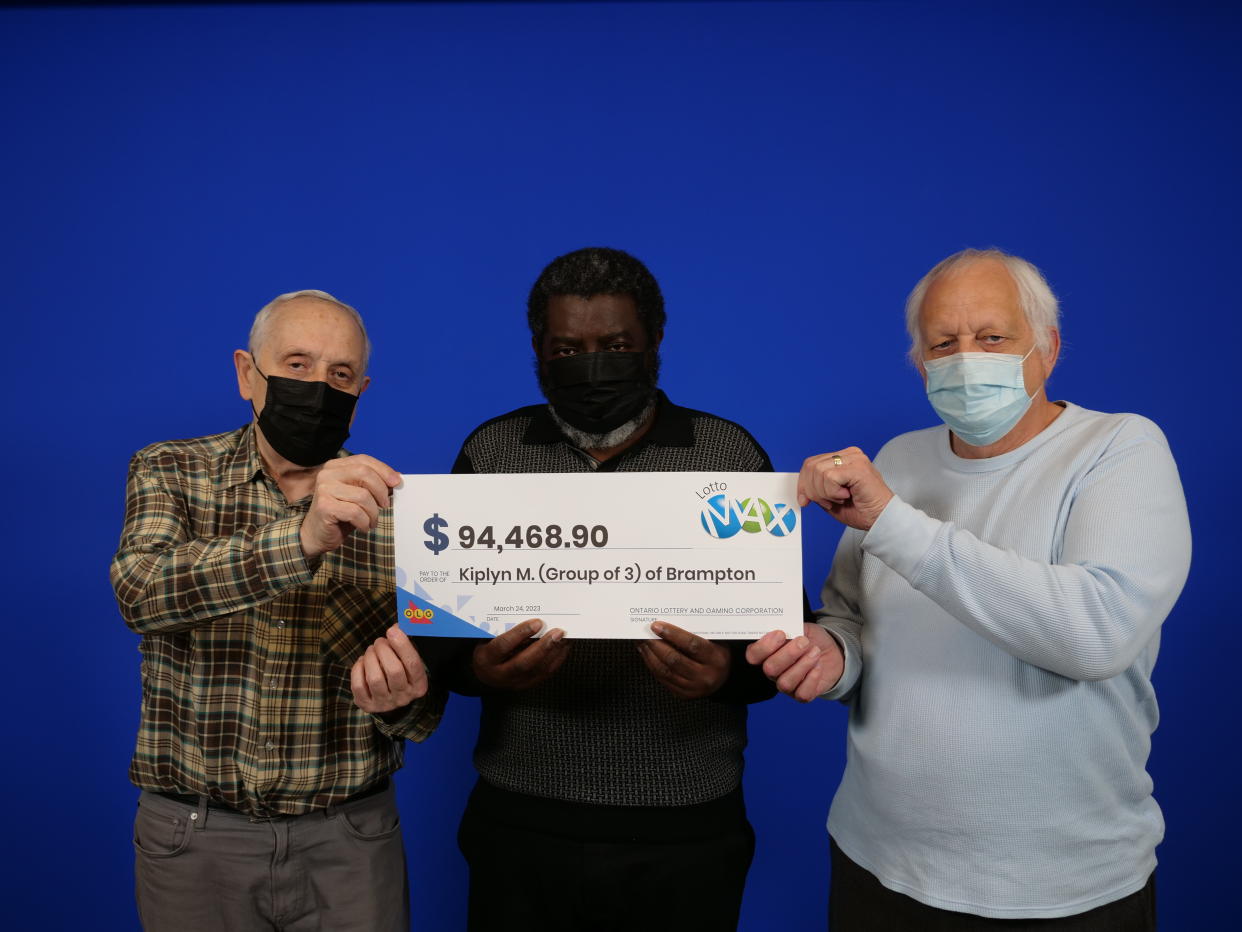 Three coworkers hold a Lotto Max cheque worth $94,468.90