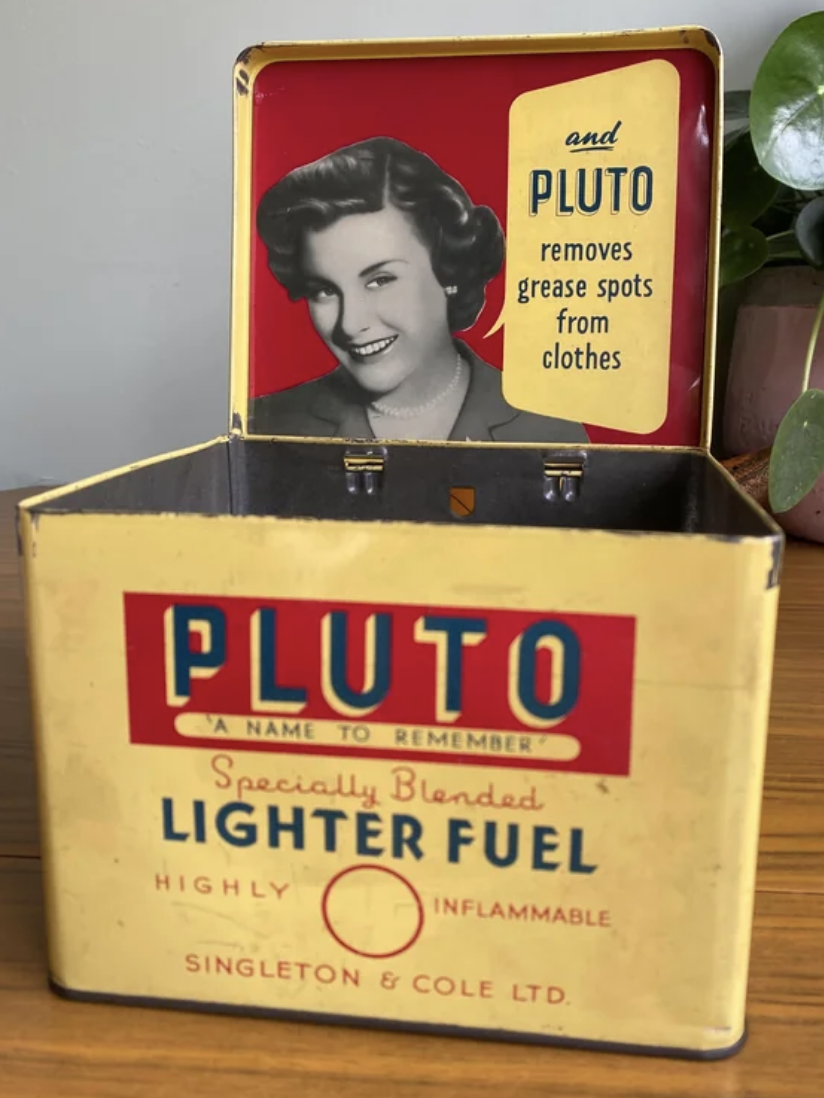 Vintage Pluto lighter fuel tin featuring a smiling woman's portrait and branding text that advertises it for use against stains