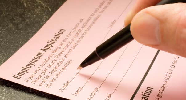 Man s hand filling out an employment application with a ballpoint pen