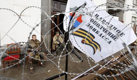 Pro-Russian armed men sit at the entrance to the regional government headquarters in Luhansk, eastern Ukraine, April 30, 2014. REUTERS/Vasily Fedosenko