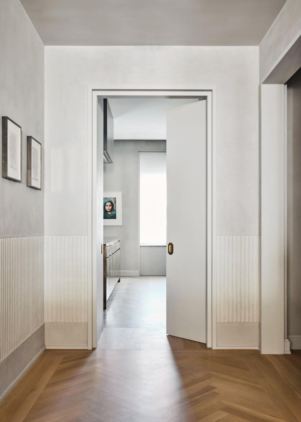 A hallway with textured plaster walls with ribbed detail panel across the bottom half