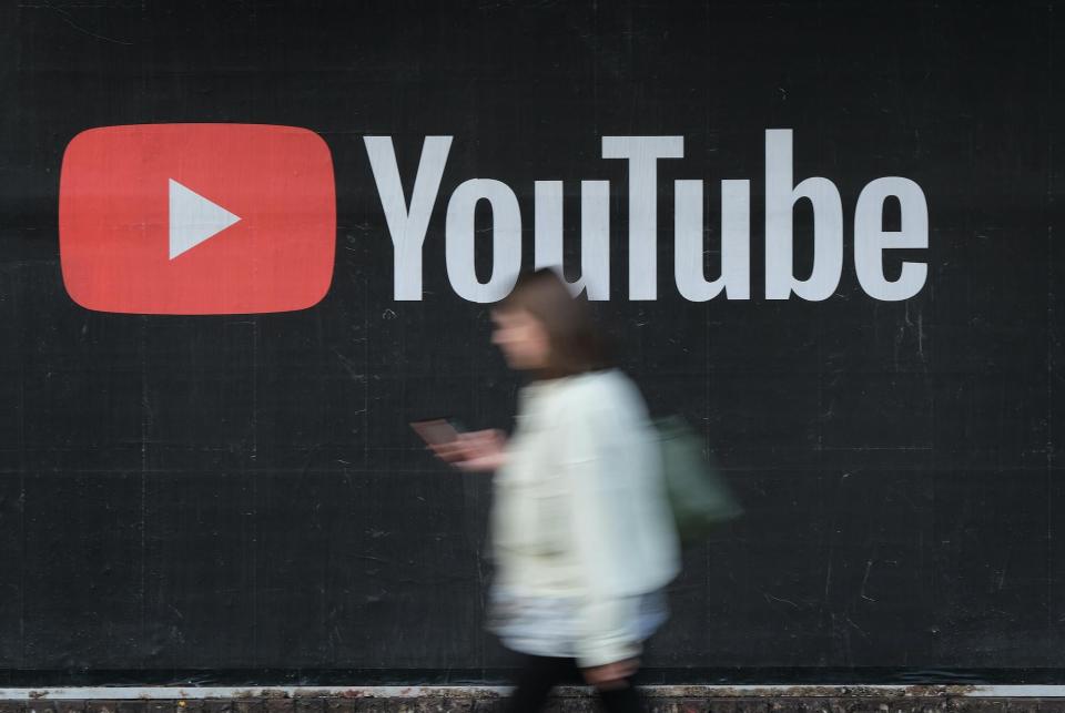 A young woman with a smartphone walks past a billboard advertisement for YouTube on September 27, 2019 in Berlin, Germany: Sean Gallup/Getty Images