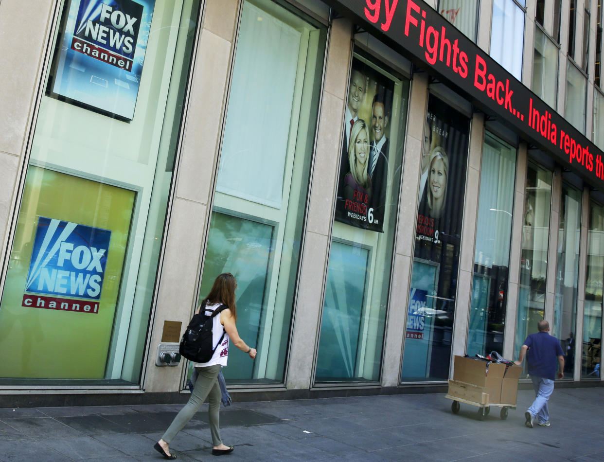 FILE- People pass the News Corporation headquarters building and Fox News studios in New York on Aug. 1, 2017.  New York City's human rights commission has fined Fox News $1 million for violation of laws protecting against sexual harassment and job retaliation. It's the largest such penalty in the commission's history.  (AP Photo/Richard Drew, File)