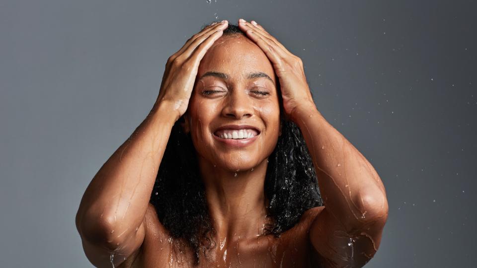 woman with curly hair washing under a shower