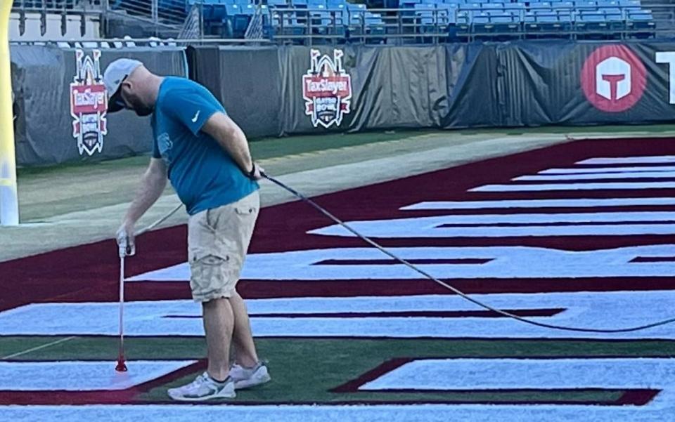 A TIAA Bank Field worker carefully paints South Carolina's colors onto one of the end zones at TIAA Bank Field in preparation for Friday's TaxSlayer Gator Bowl game.
