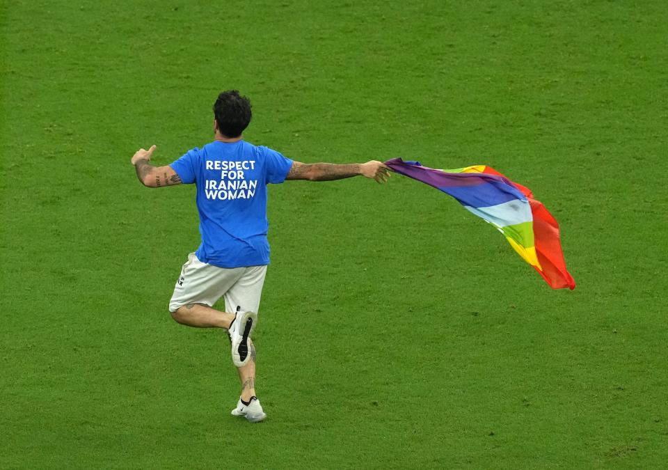 A protestor in a top reading "Respect For Iranian Women" waving a rainbow flag invades the pitch during the FIFA World Cup Group H match at the Lusail Stadium in Lusail, Qatar.