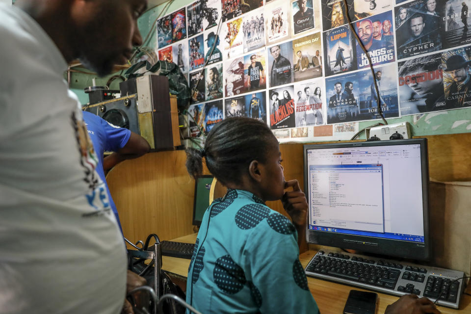 An Internet cafe owner, left, stands nearby as a customer, right, uses a computer at an internet cafe in the low-income Kibera neighborhood of Nairobi, Kenya Wednesday, Sept. 29, 2021. Instead of serving Africa's internet development, millions of internet addresses reserved for Africa have been waylaid, some fraudulently, including in insider machinations linked to a former top employee of the nonprofit that assigns the continent's addresses. (AP Photo/Brian Inganga)