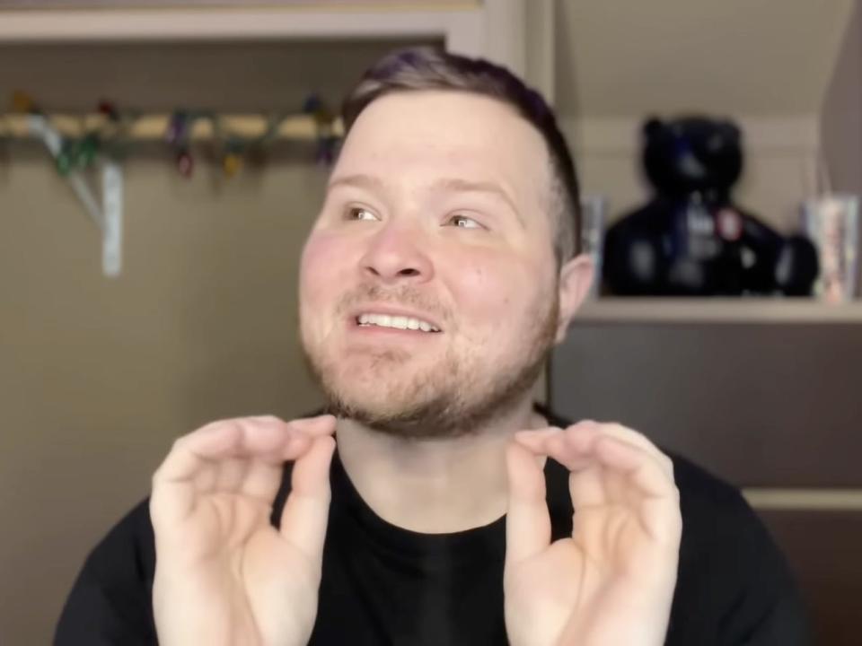 A screenshot from a Dustin Dailey video, where he's seated in a closet wearing a black T-shirt.