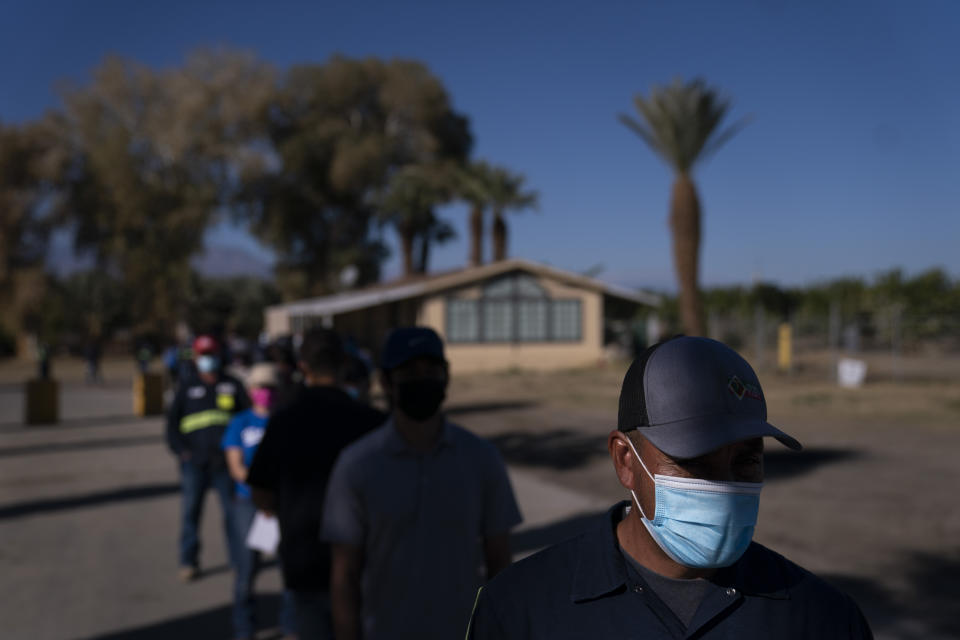 Hispanic farm workers wait in line to receive the Pfizer-BioNTech COVID-19 vaccine in Mecca, Calif., Thursday, Jan. 21, 2021. The farmworkers who got their shots are among the millions of immigrants around the United States, who advocacy groups warn may be some of the most difficult people to reach during the largest vaccination campaign in American history. (AP Photo/Jae C. Hong)