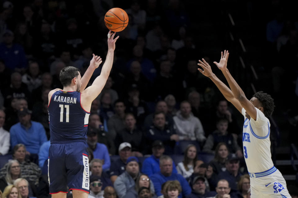 UConn forward Alex Karaban, left, attempts a 3-point basket against Xavier's guard Dailyn Swain, right, during the first half of an NCAA college basketball game Wednesday, Jan. 10, 2024, in Cincinnati. (AP Photo/Aaron Doster)