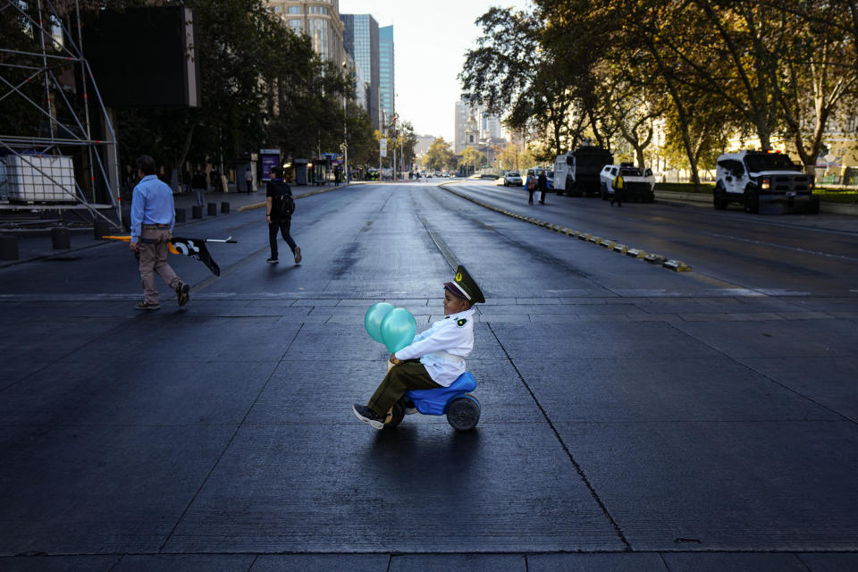 A child dressed as a police officer and accompanied by his parents, rides his toy vehicle to a demonstration seeking justice for police officers killed in the line of duty, in Santiago, Chile, April 27, 2024. (AP Photo/Esteban Felix)