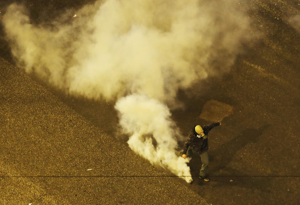A protester runs to throw back a tear gas canister fired by riot police during clashes following a rally by opponents of Prespa Agreement, outside the Greek Parliament in Athens, Thursday, Jan. 24, 2019. Greek lawmakers are debating a historic agreement aimed at normalising relations with Macedonia in a stormy parliamentary session scheduled to culminate in a Friday vote. (AP Photo/Thanassis Stavrakis)