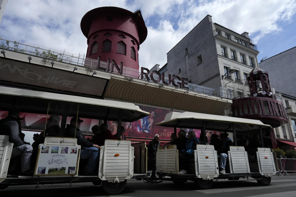 A tourists train drives past the Moulin Rouge (Red Mill) Thursday, April 25, 2024 in Paris. The windmill from the Moulin Rouge, the 19th century Parisian cabaret, has fallen off the roof overnight along with some of the letters in its name. (AP Photo/Thibault Camus)