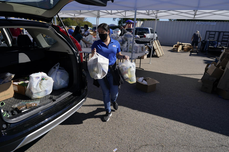 A volunteer loads food into a car at an Armed Services YMCA food distribution, Oct. 28, 2021, in San Diego. As many of 160,000 active duty military members are having trouble feeding their families, according to Feeding America, which coordinates the work of more than 200 food banks around the country. (AP Photo/Gregory Bull)