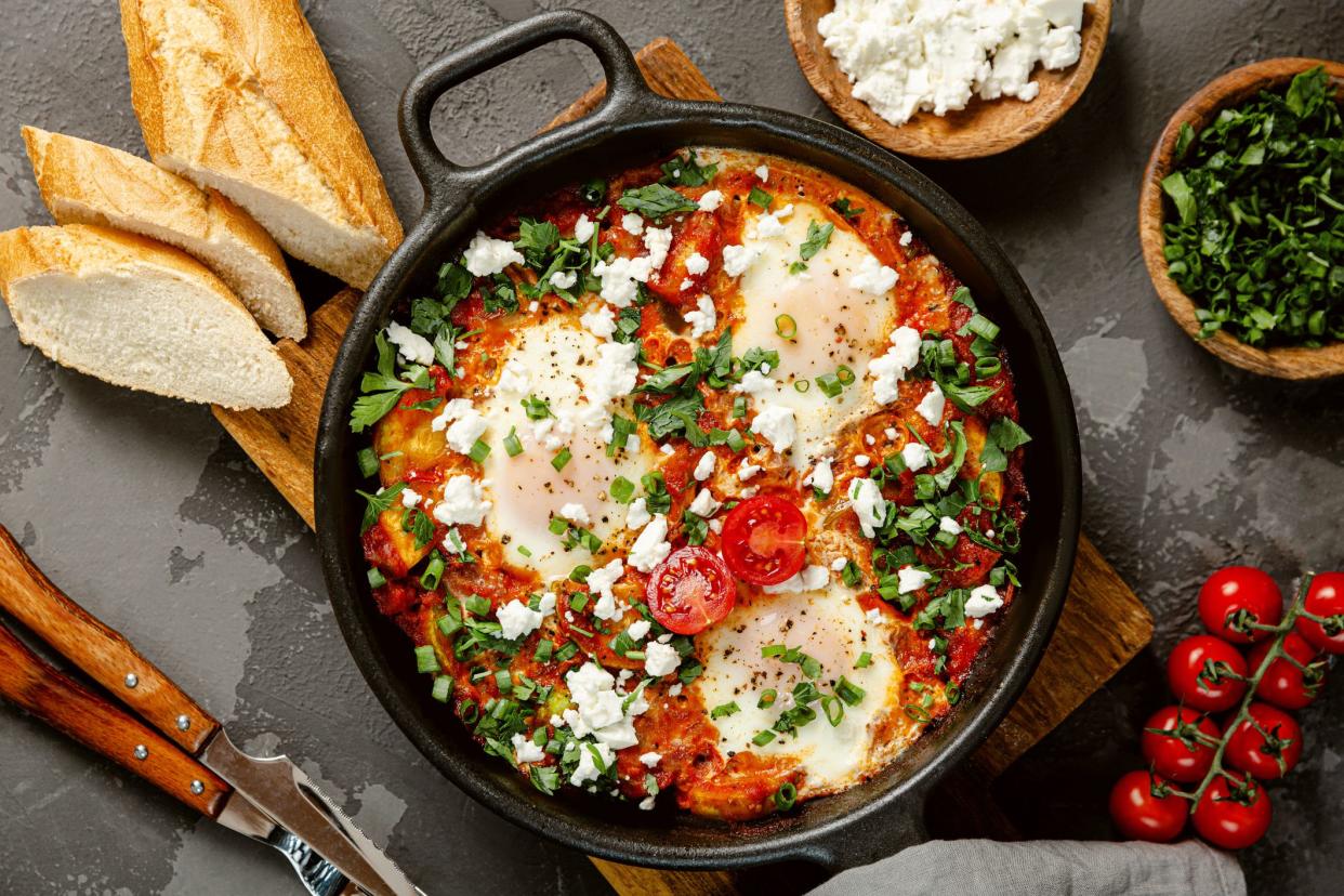 Shakshuka, fried eggs with tomatoes, onion, red pepper and spices in cast iron pan. Top view.