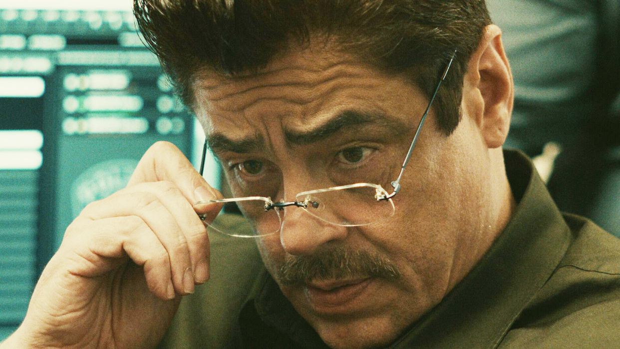 a man wearing glasses benicio del toro, reptile