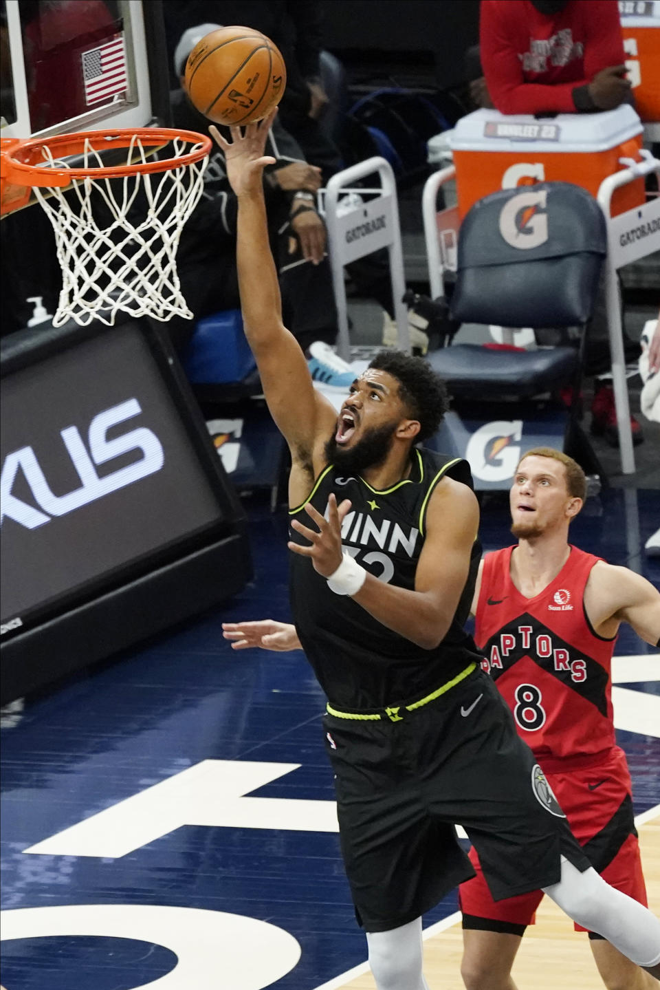 Minnesota Timberwolves' Karl-Anthony Towns (32) lays up a shot as Toronto Raptors' Malachi Flynn (8) watches during the second half of an NBA basketball game Friday, Feb. 19, 2021, in Minneapolis. (AP Photo/Jim Mone)