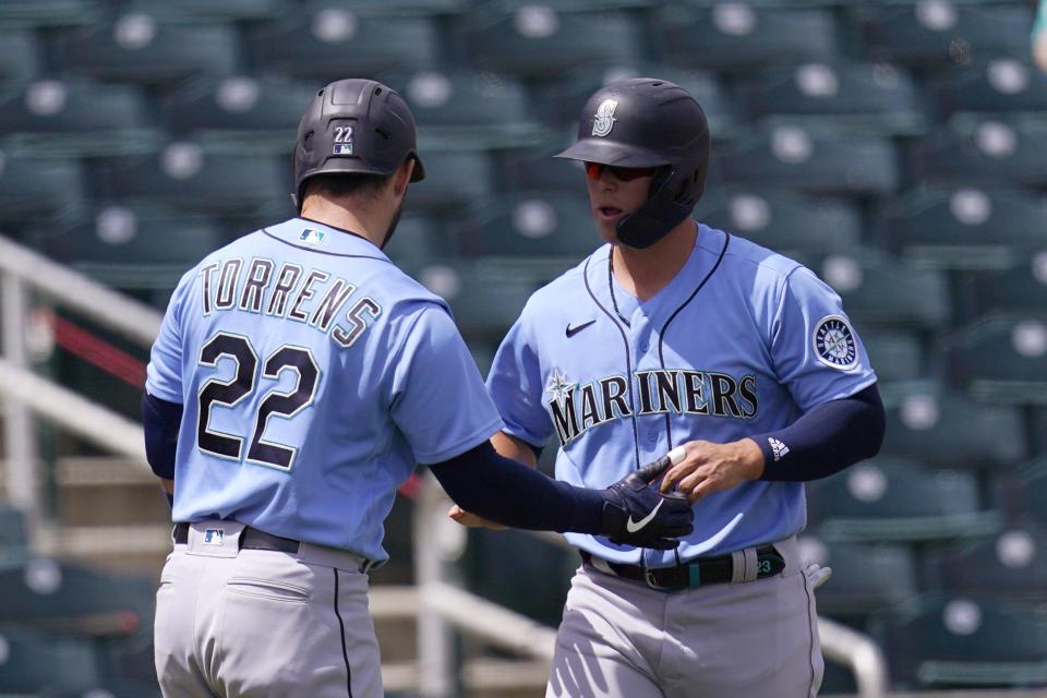 Seattle Mariners' Ty France, right, celebrates his run scored against the Cincinnati Reds with teammate Luis Torrens, left, during the first inning of a spring training baseball game Monday, March 29, 2021, in Goodyear, Ariz. (AP Photo/Ross D. Franklin)