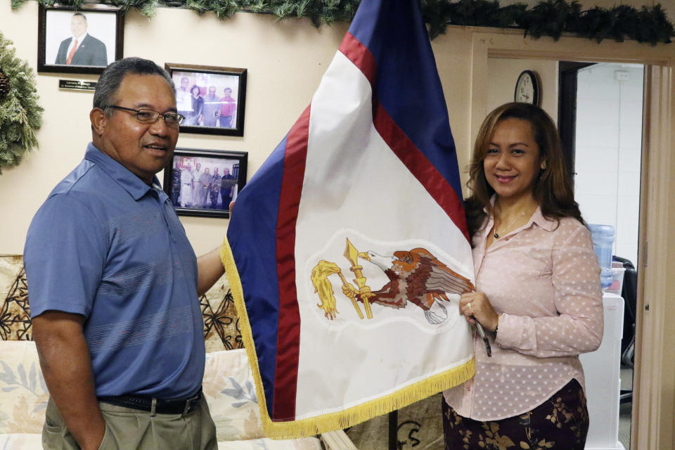 FILE - In this Jan. 10, 2020 file photo, Filipo Ilaoa, left, and Bonnelley Pa'uulu pose with the flag of American Samoa at the American Samoa government office in Honolulu. A federal appeals court ruling says U.S. citizenship shouldn't be imposed on those born in American Samoa. The decision reverses a lower court ruling that sided with three people from American Samoa who lived in Utah. They sued to be recognized as citizens. (AP Photo/Jennifer Sinco Kelleher, File)