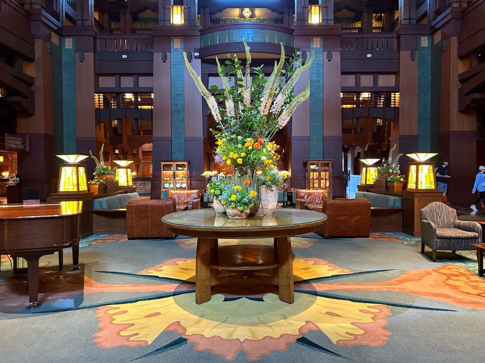 The lobby of Disneyland's Grand Californian Hotel, with brown walls, ample seating, and a large floral arrangement.