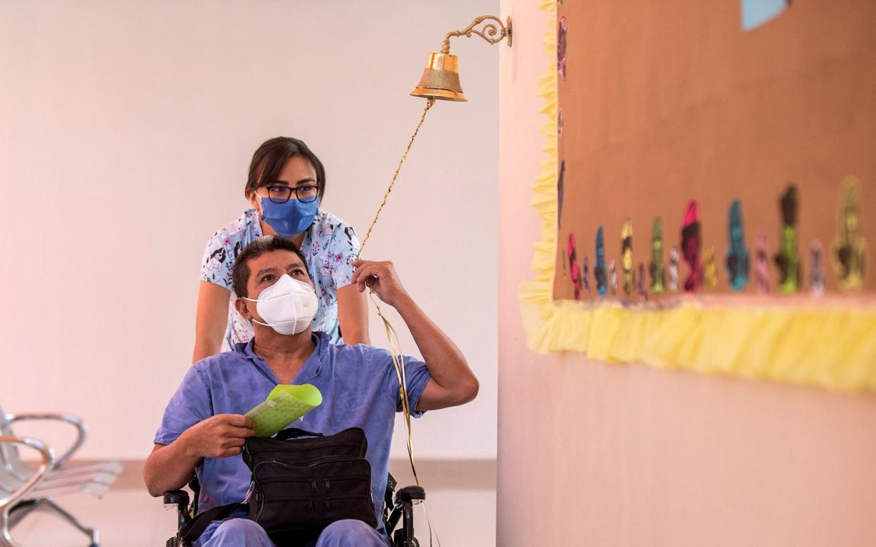 A patient who has recovered from a severe Covid-19 infection rings a bell in a sign of victory as he leaves hospital - but experts say people can continue to experience persistent symptoms two months after testing negative - MIGUEL SIERRA/EPA-EFE/Shutterstock