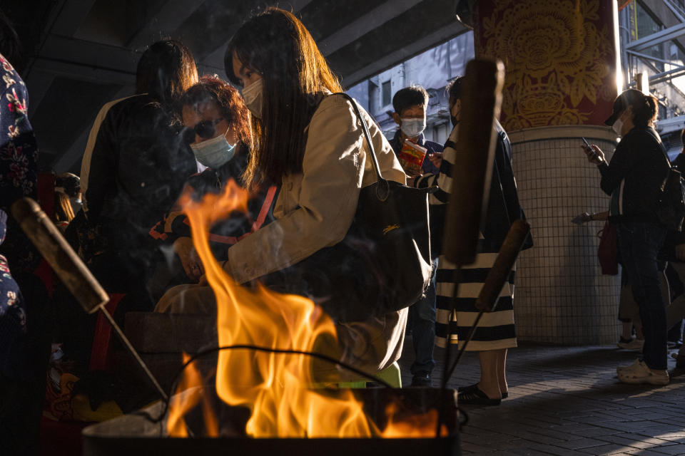 Customers watch a "villain hitting" ceremony on the day of "ging zat," as pronounced in Cantonese, which on the Chinese lunar calendar literally means "awakening of insects," under the Canal Road Flyover in Hong Kong on Monday, March 6, 2023. (AP Photo/Louise Delmotte)