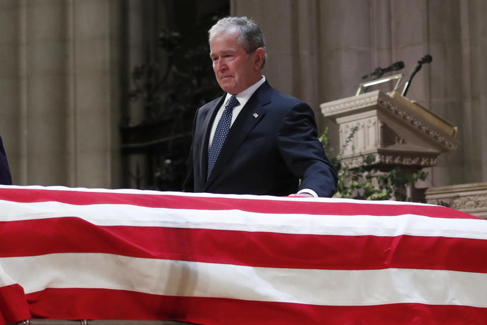 Former President George W. Bush touches the casket of his father, former President George H.W. Bush, at the State Funeral at the Washington National Cathedral.