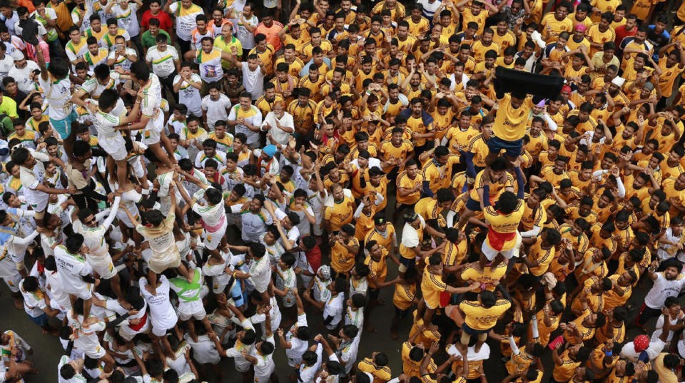 <p>Indian devotees show a black flag standing on the top of a human pyramid before breaking dahi handi, a pot filled with curd, during a protest against an Indian court order imposing height restrictions on human pyramids formed during the festivities and banning youngsters below 18 years from participating, in Mumbai, India, Aug. 25, 2016. The holiday marks the birth of the Hindu God Krishna. (Photo: Rafiq Maqbool/AP) </p>