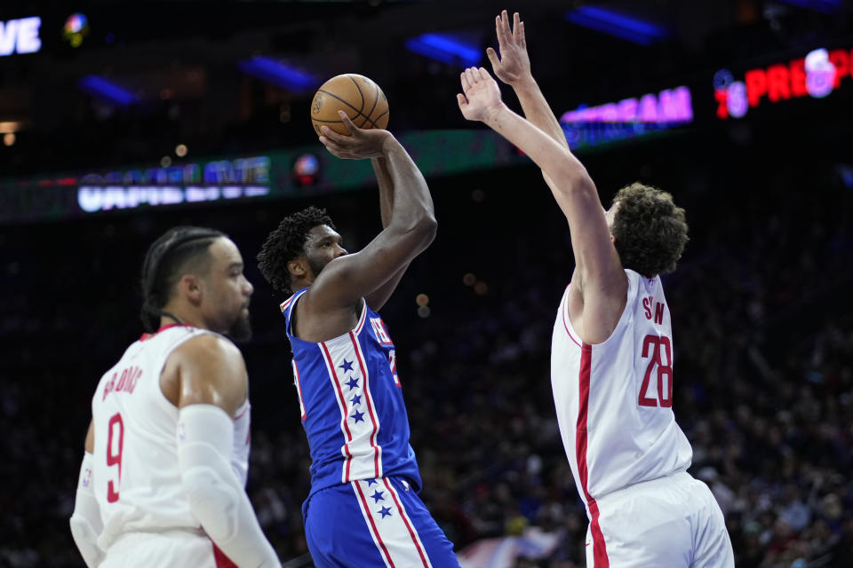 Philadelphia 76ers' Joel Embiid, center, goes up for a shot between Houston Rockets' Alperen Sengun, right, and Dillon Brooks during the first half of an NBA basketball game, Monday, Jan. 15, 2024, in Philadelphia. (AP Photo/Matt Slocum)