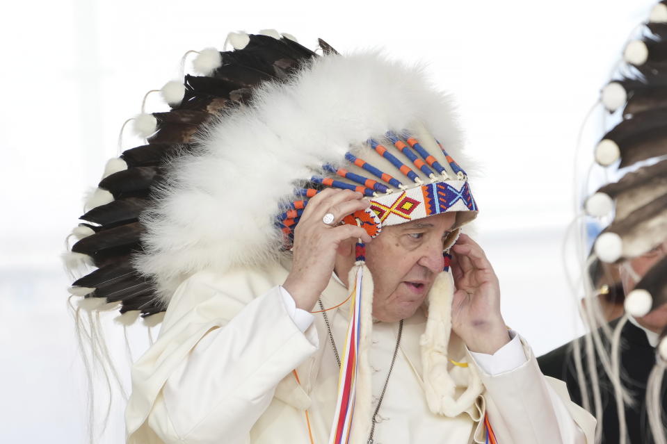 Pope Francis adjusts a traditional headdress he was given after his apology to Indigenous people for the church's role in residential schools during a ceremony in Maskwacis, Alberta, as part of his papal visit across Canada on Monday, July 25, 2022. (Nathan Denette/The Canadian Press via AP)