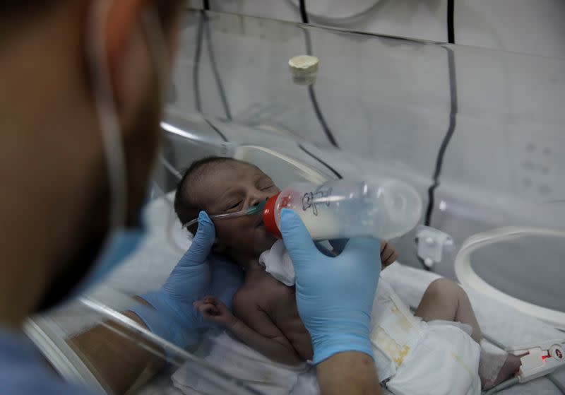 A nurse bottle feeds a premature baby at a maternity hospital in Idlib