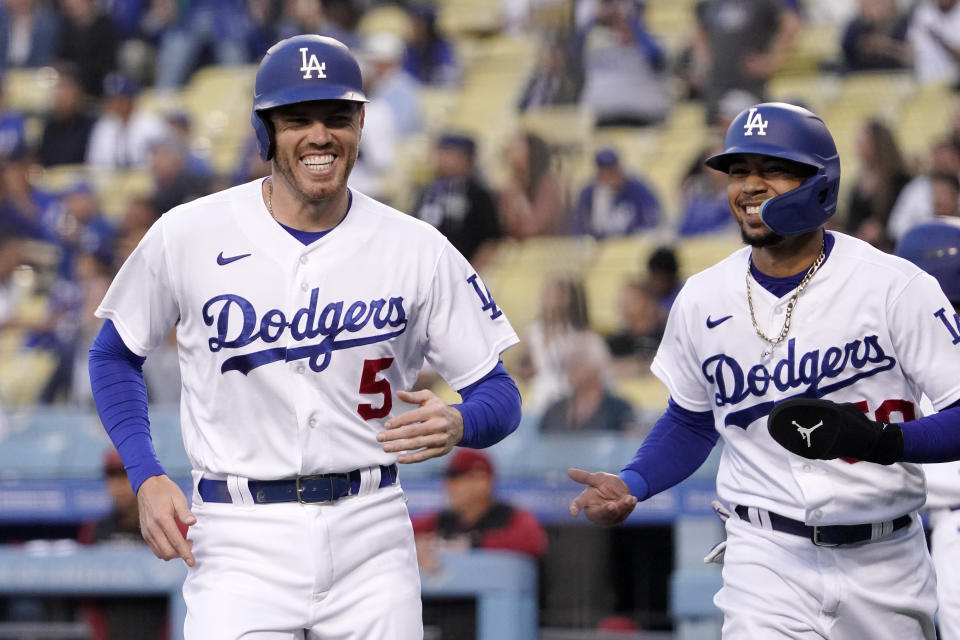 FILE -Los Angeles Dodgers' Freddie Freeman, left, and Mookie Betts laugh after they scored on a single by Trea Turner during the first inning of a baseball game against the Arizona Diamondbacks Tuesday, May 17, 2022, in Los Angeles. The Los Angeles Dodgers were hit with a $32 million luxury tax for the second straight season, among six teams paying a penalty as baseball payrolls rebounded after the lockout to a record $4.56 billion.(AP Photo/Mark J. Terrill, File)