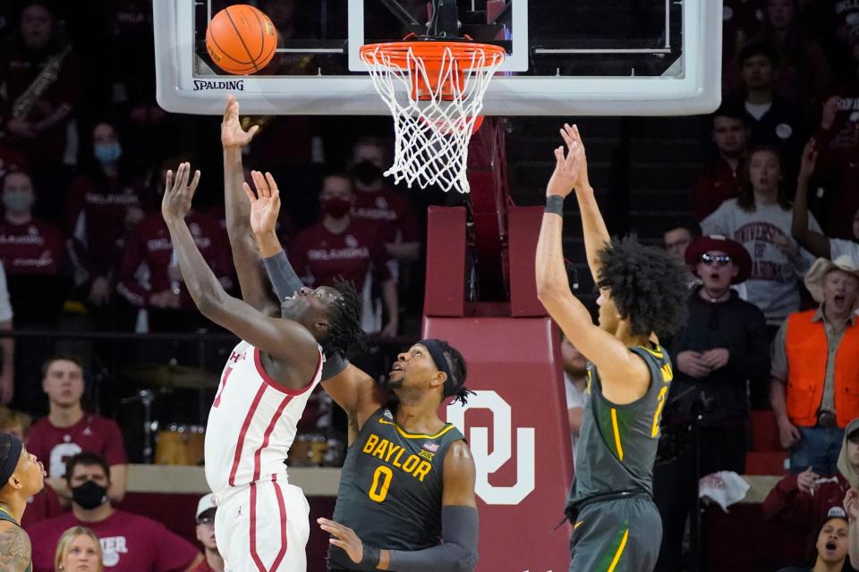 Oklahoma forward Akol Mawein, left, shoots in front of Baylor forward Flo Thamba (0) and guard Kendall Brown, right, in the first half of an NCAA college basketball game Saturday, Jan. 22, 2022, in Norman, Okla. (AP Photo/Sue Ogrocki)
