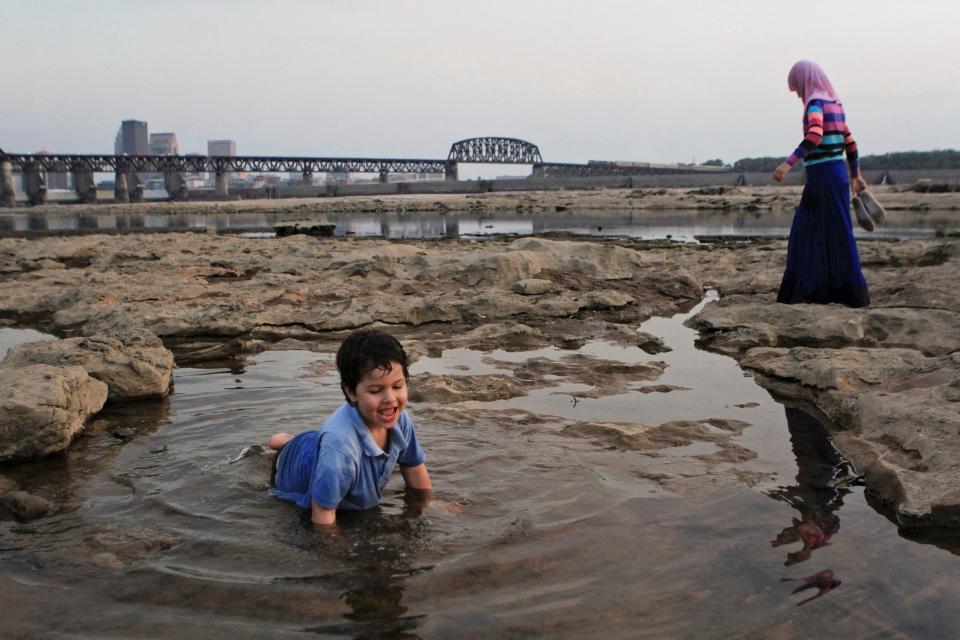 Ibraham Alsaadi plays in a water-filled hole while sister Mahasen Alsaadi, 9, walks nearby as the two recently were visiting the Falls of the Ohio fossil bed. The 390-million-year-old fossil bed is considered the largest Devonian fossil bed in the world. Thousands of visitors from Indiana and Louisville explore the unique area every year.