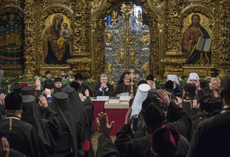 Ukrainian President Petro Poroshenko, center left, and Metropolitan Emmanuel, center right, attend a closed-door synod of three Ukrainian Orthodox churches to approve the charter for a unified church and to elect leadership in the St. Sophia Cathedral in Kiev, Ukraine, Saturday, Dec. 15, 2018. Poroshenko has told the crowd "the creation of our Church is another declaration of Ukraine's independence and you are the main participants of this historic event." (Mykhailo Markiv, Ukrainian Presidential Press Service/Pool Photo via AP)