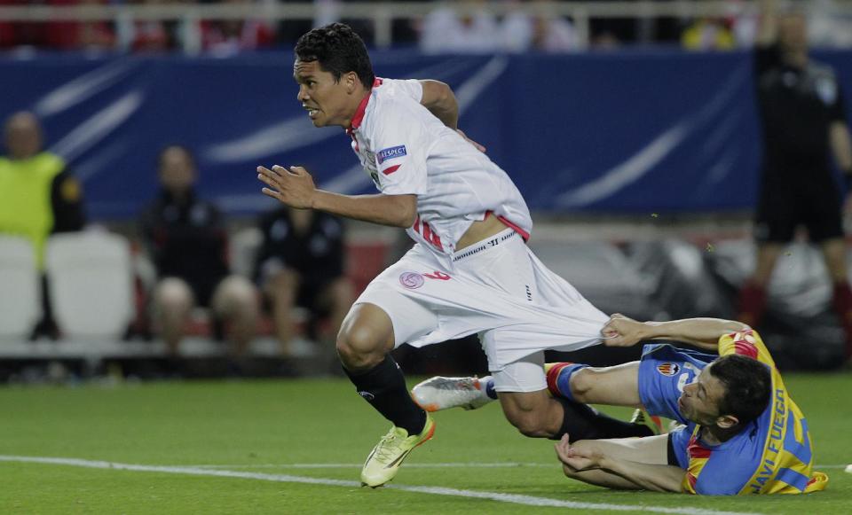 Sevilla's Carlos Bacca, left, and Valencia's Javi Fuego, right, fight for the ball during their Europa League semifinal first leg soccer match at the Ramon Sanchez Pizjuan stadium, in Seville, Spain on Thursday, April 24, 2014. (AP Photo/Miguel Angel Morenatti)