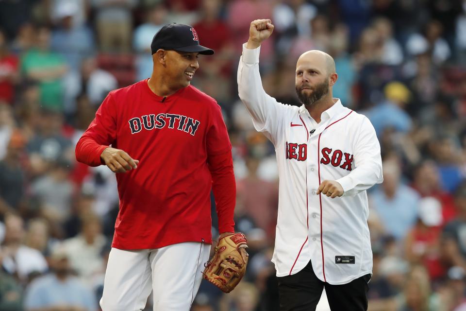 Former Boston Red Sox's Dustin Pedroia, right, walks off the field after throwing out the ceremonial first pitch to manager Alex Cora, left, before a baseball game against the New York Yankees, Friday, June 25, 2021, in Boston. (AP Photo/Michael Dwyer)