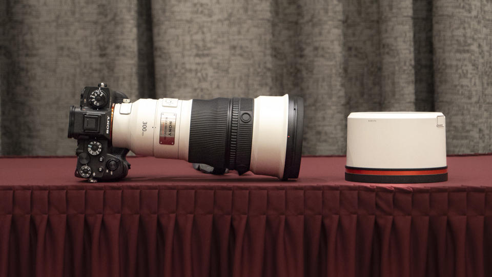 Sony FE 300mm F2.8 GM OSS lens on a red table alongside lens hood