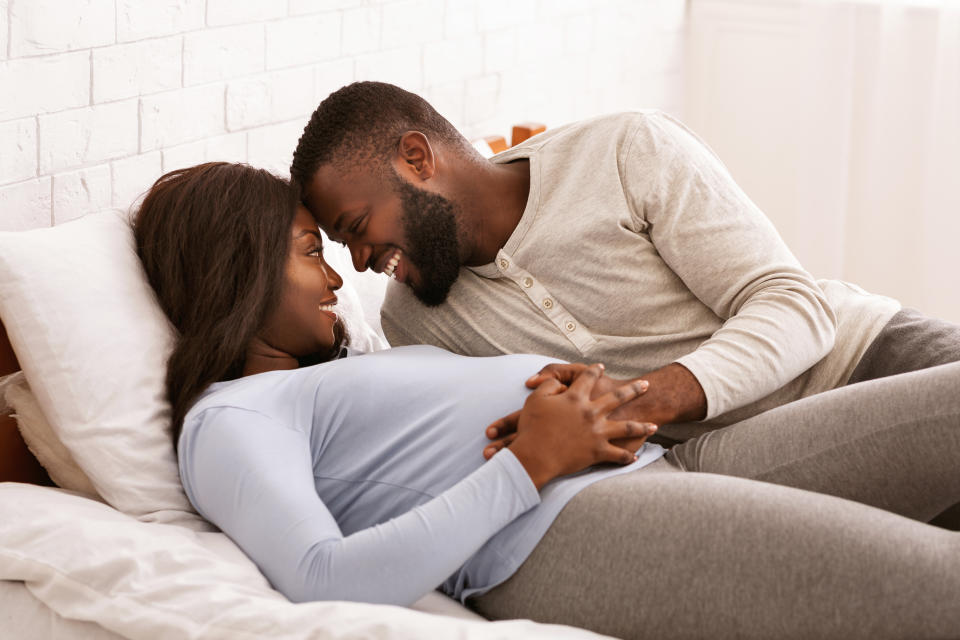 Pregnant black couple in love cuddling in bed at home, love and passionate concept. While it's fine for most couples, there are reasons why some may want to abstain from sex. (Getty)