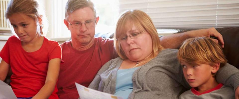 Unhappy Family Sitting On Sofa Looking At Bills