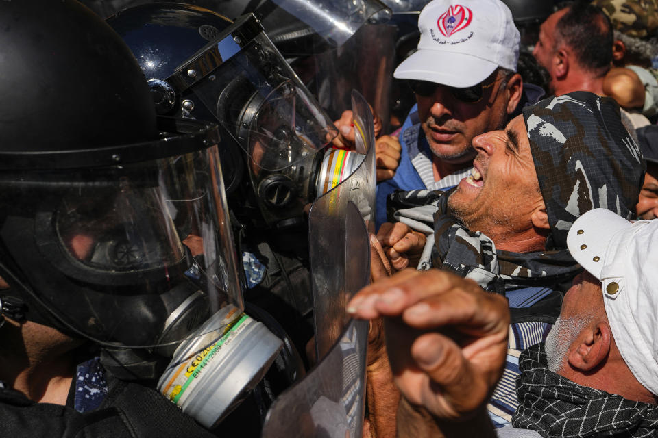 Retired members of the Lebanese security forces and other protesters scuffle with riot police after they removed a barbed-wire barrier in order to advance towards government buildings during a protest in Beirut, Lebanon, Tuesday, April 18, 2023. Earlier in the day, Lebanon's Parliament voted to postpone municipal elections in the crisis-stricken country that had been planned for May 2023 by up to a year. (AP Photo/Hassan Ammar)